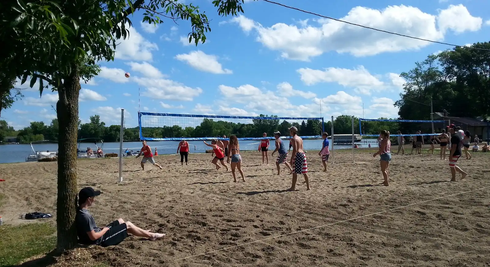 People playing sand volleyball beside the lake